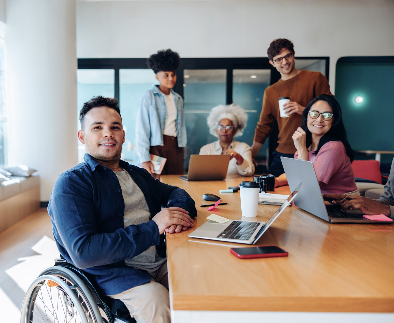 Profissional em cadeira de rodas com sua equipe em um ambiente de trabalho colaborativo